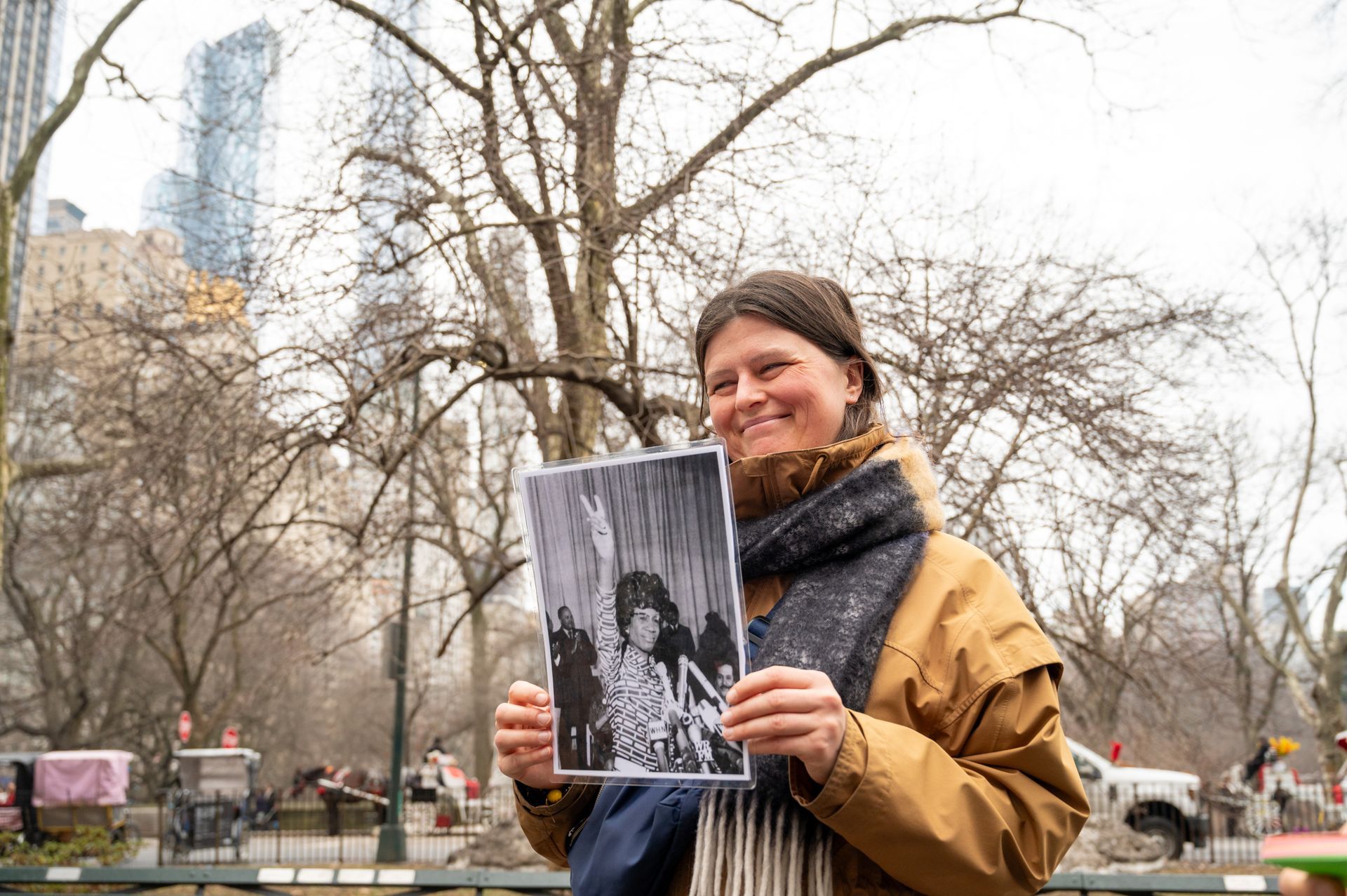 A NYC women's history guest holds up a picture of Shirley Chisholm in Central Park.