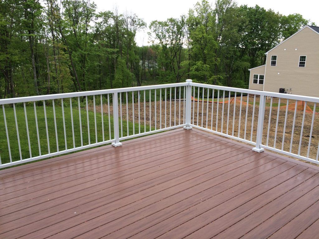 A deck with a white railing and a house in the background by Premier Decks & Awnings
