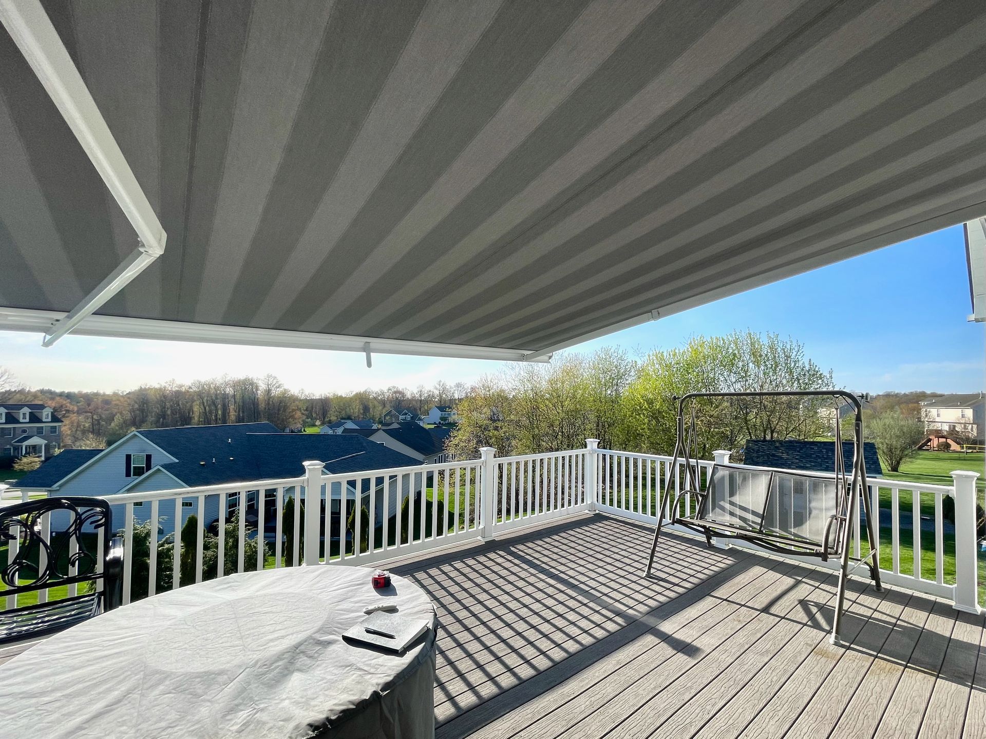 A deck with a table and chairs under an awning by Premier Decks & Awnings