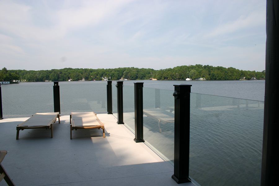 A dock with chairs and a view of a lake by Premier Decks & Awnings