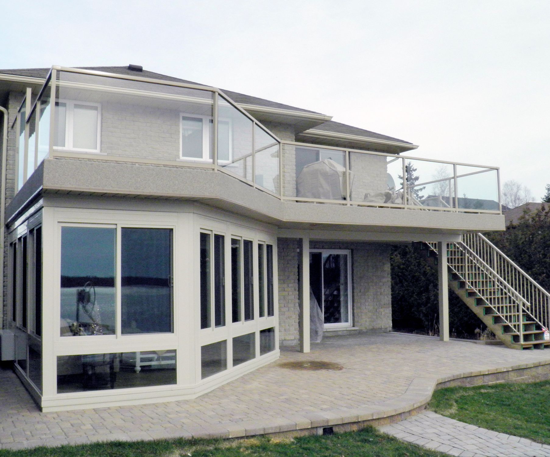 A house with a large deck and stairs leading up to it by Premier Decks & Awnings