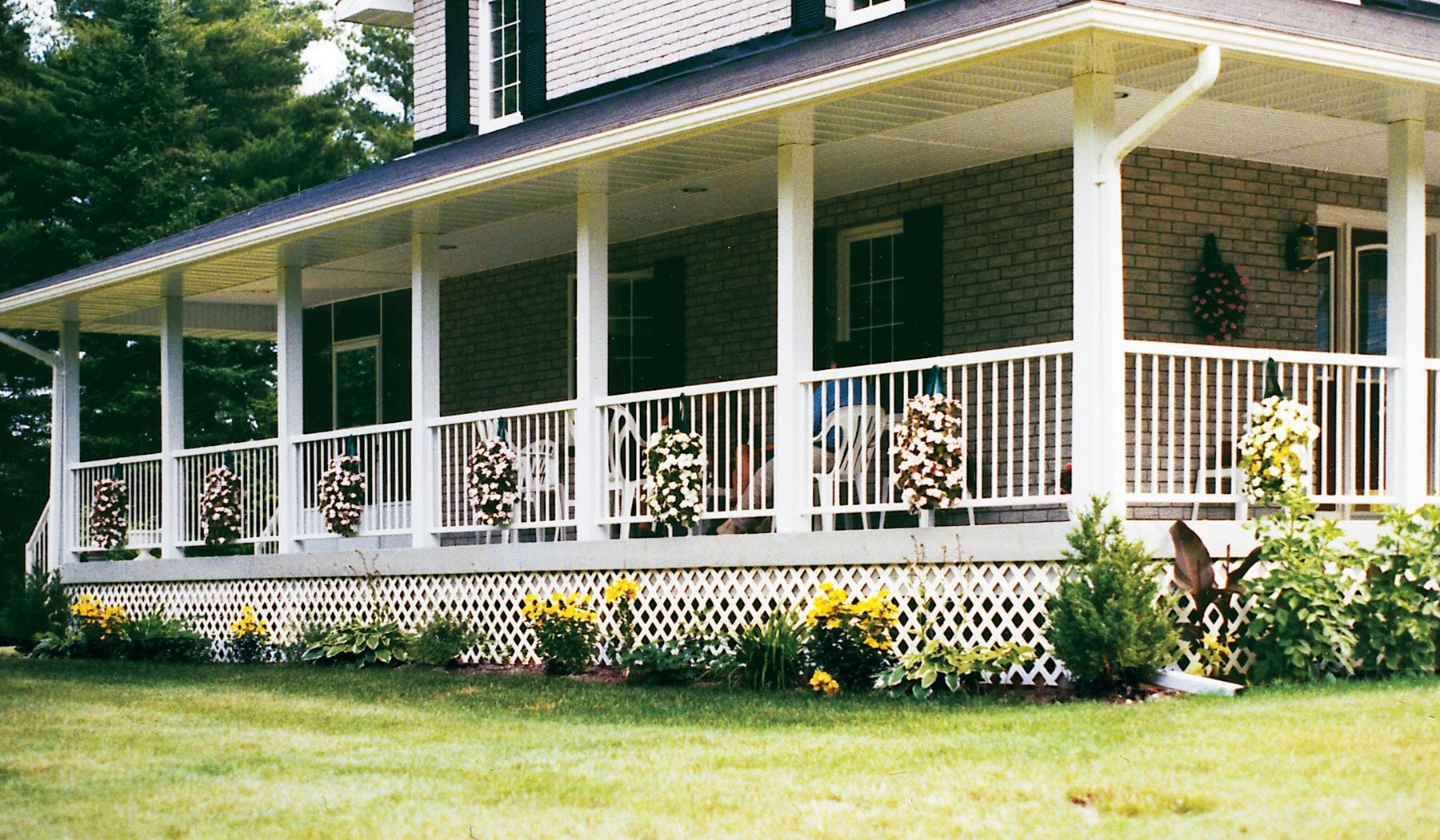 The front porch of a house with a white railing by Premier Decks & Awnings