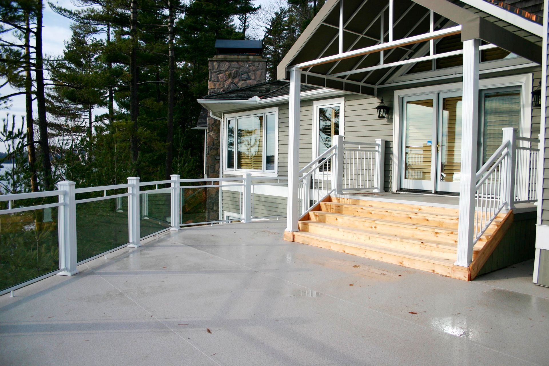 A large house with a large deck and stairs by Premier Decks & Awnings