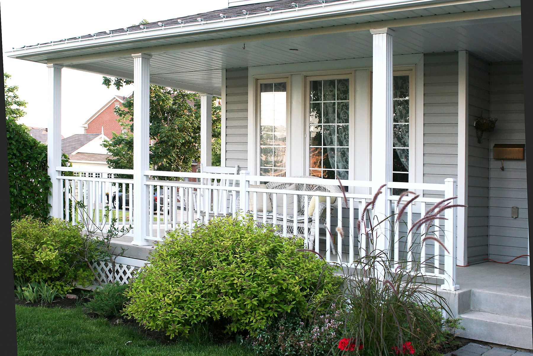 A white house with a porch and a mailbox by Premier Decks & Awnings