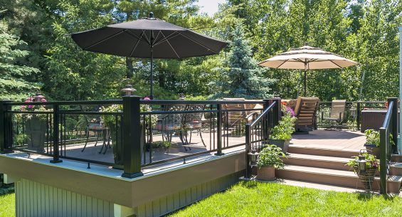 There is a deck with umbrellas and chairs on it by Premier Decks & Awnings