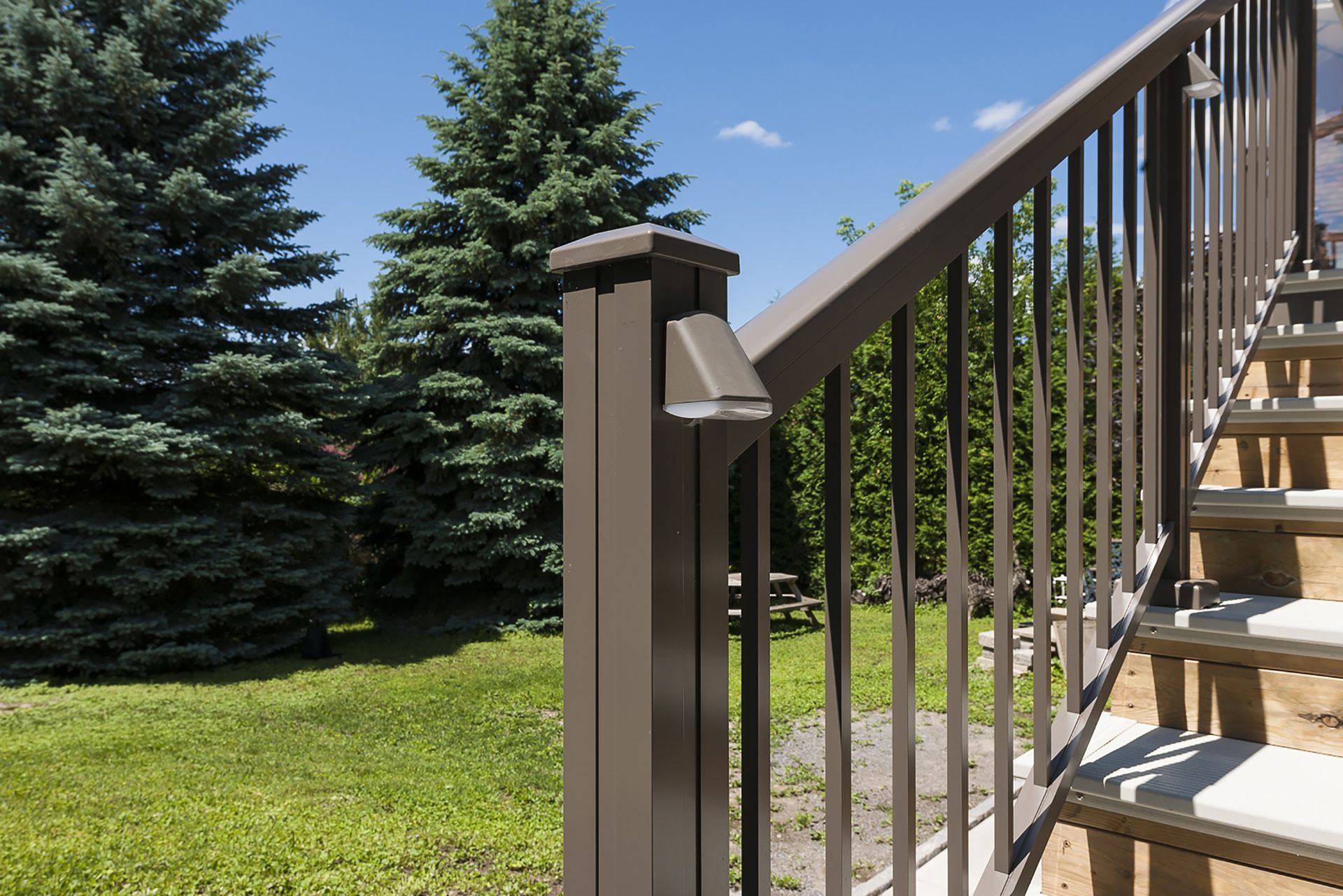 Stairs leading up to a deck with trees in the background by Premier Decks & Awnings