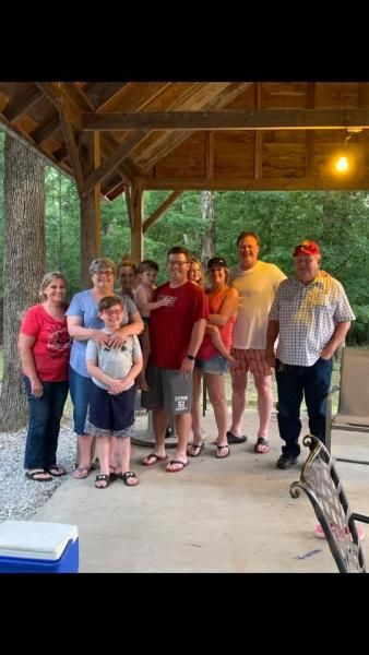 Group of people standing together under a wooden pavilion, posing for a photo in a park.