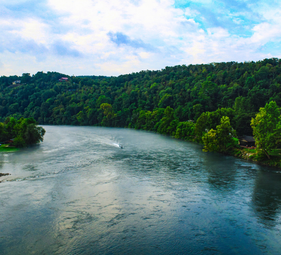 Wide river winding through green forested hills under a cloudy sky
