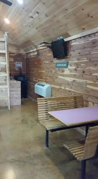 Wood-paneled dining area with benches, a table, TV, and kitchenette.