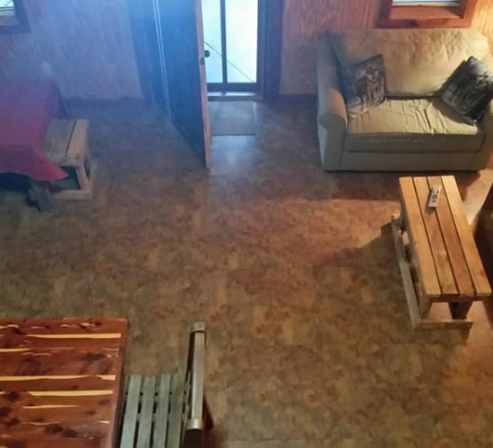 Rustic living room with couch, bench, table, and doorway on a brown floor