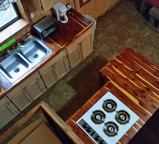 Compact kitchen with wooden counters, sink, and a four-burner stove viewed from above.