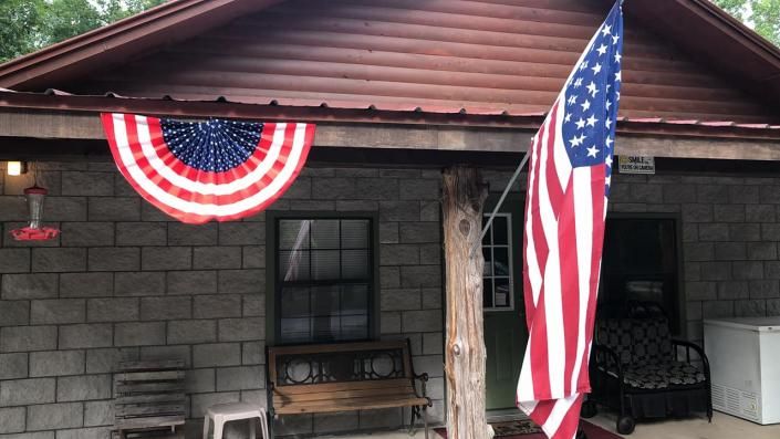 Porch of a house decorated with patriotic red, white, and blue bunting and an American flag.