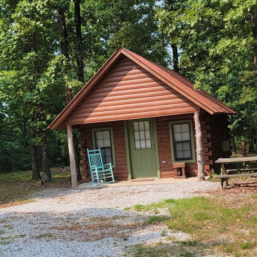 Small rustic cabin with green door and rocking chair among trees