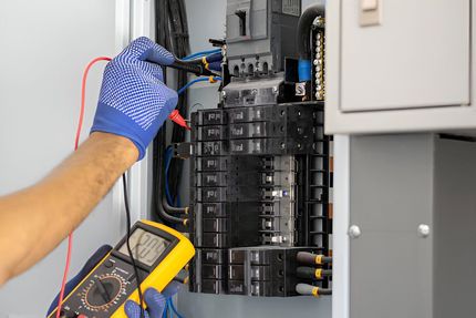 A man is using a multimeter to test an electrical box.
