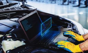 A man is working on a laptop computer in a car.