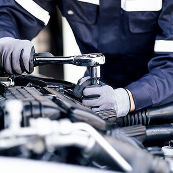 A person repairing an engine in a vehicle