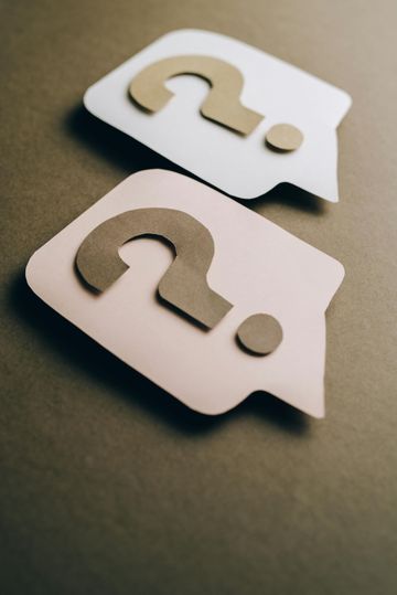 Two speech bubbles made out of wood with question marks on them