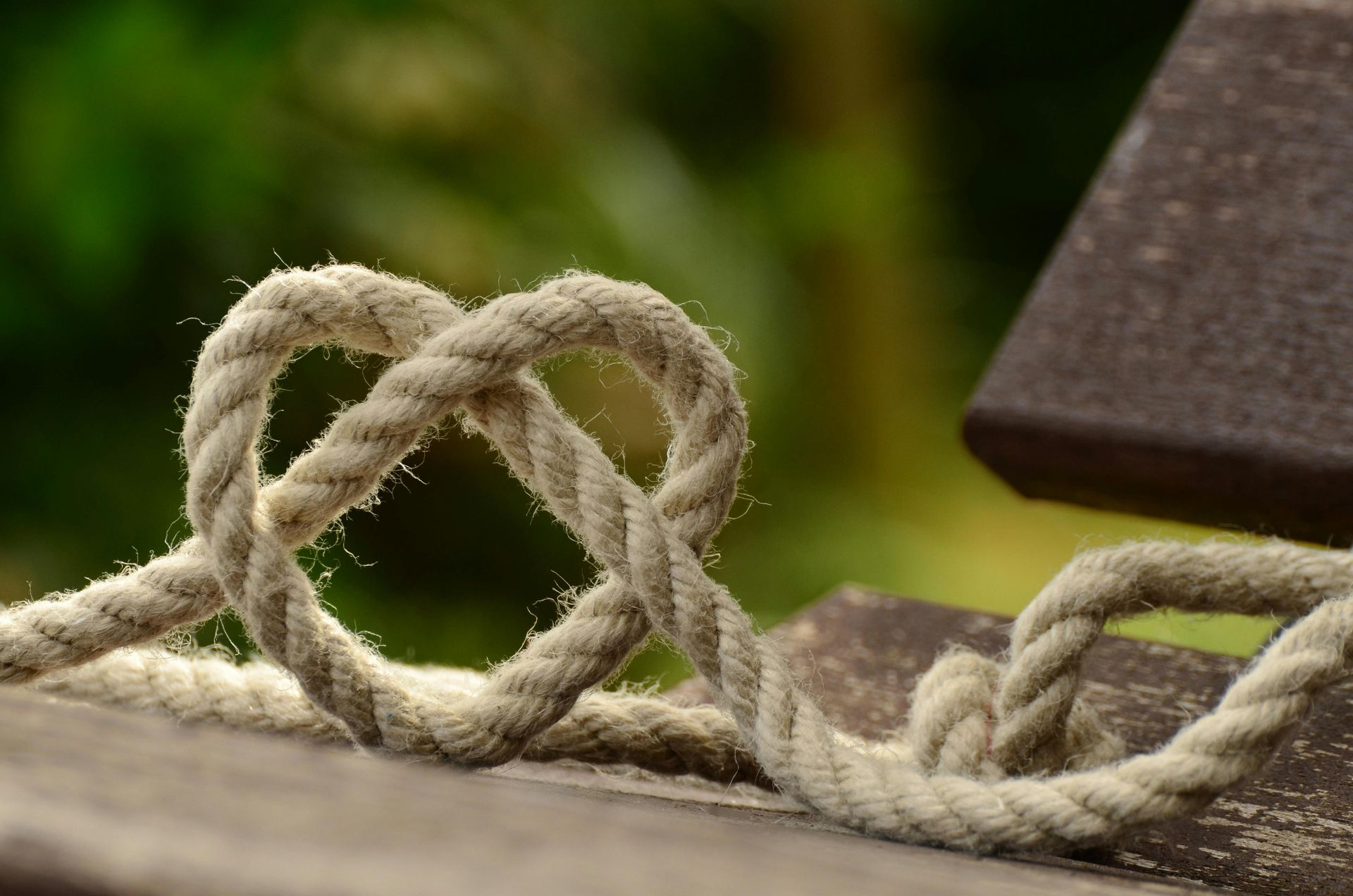 A close up of a rope in the shape of a heart on a wooden surface.