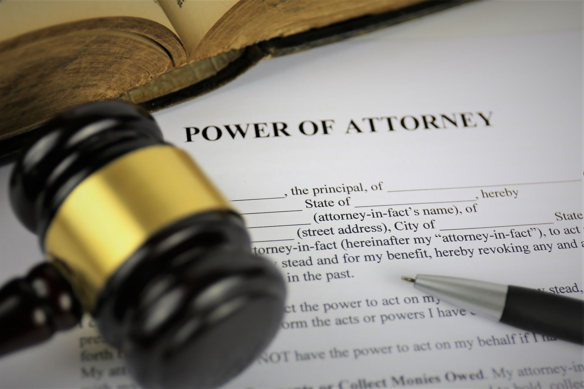 Gavel on a power of attorney document beside a pen and open book