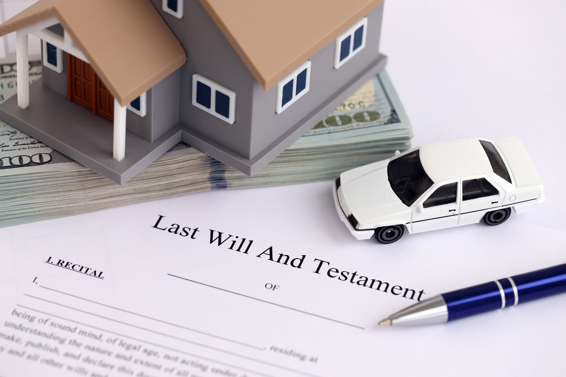 Model house, car, pen, and last will and testament document on a desk