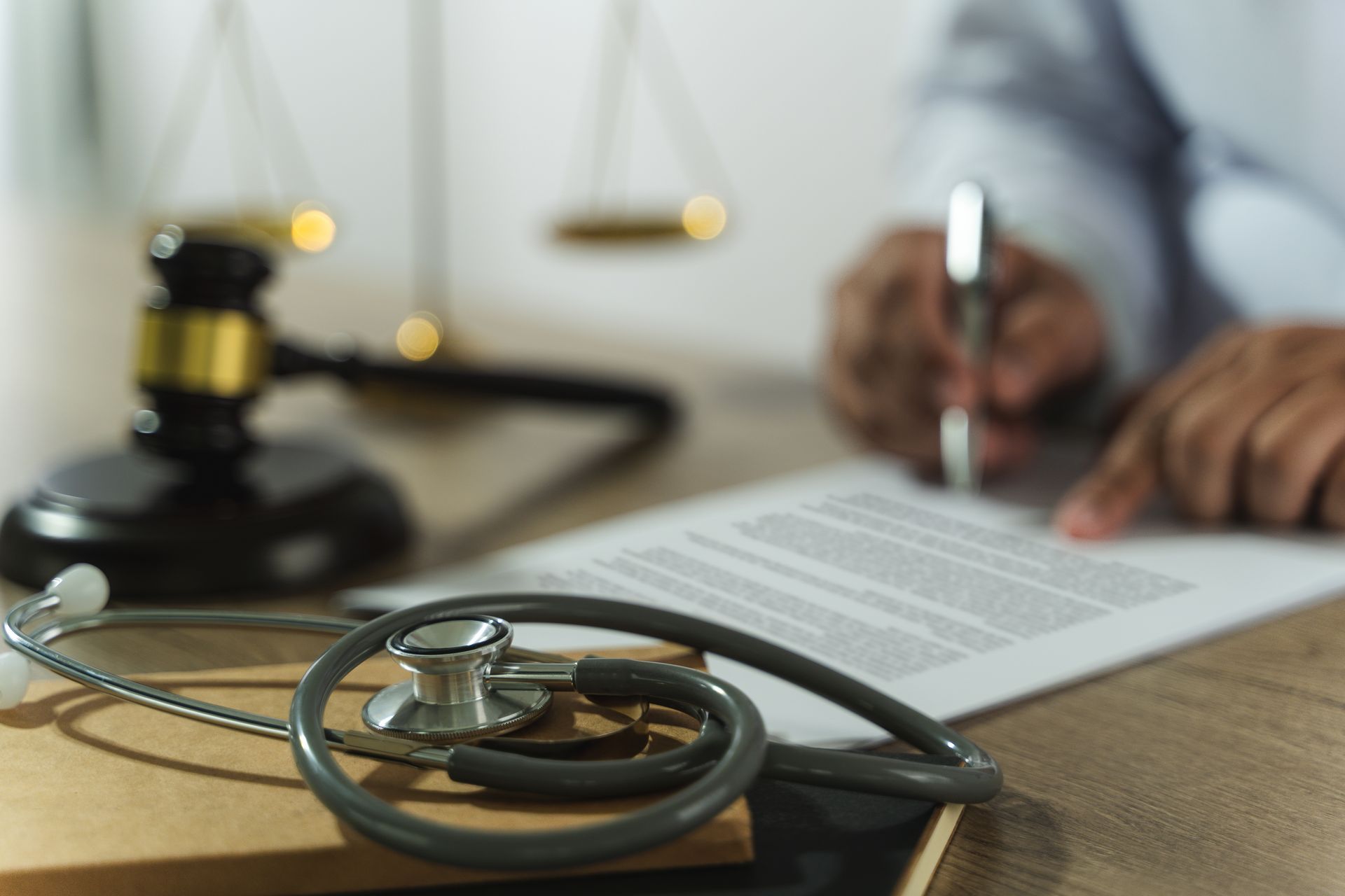 Doctor’s desk with stethoscope, gavel, and a person signing a document