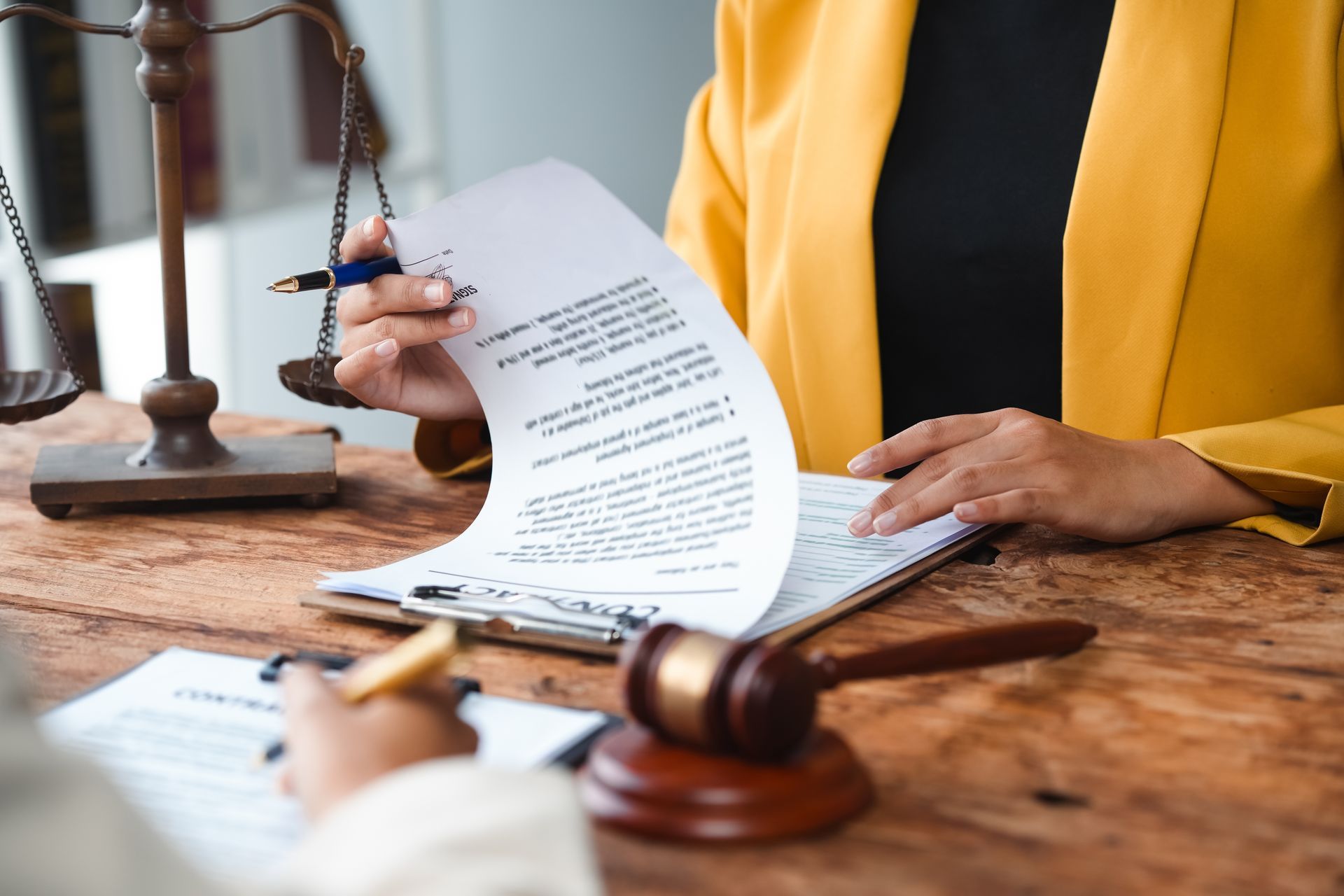 Lawyer reviewing a document at a desk with a gavel and scales of justice nearby