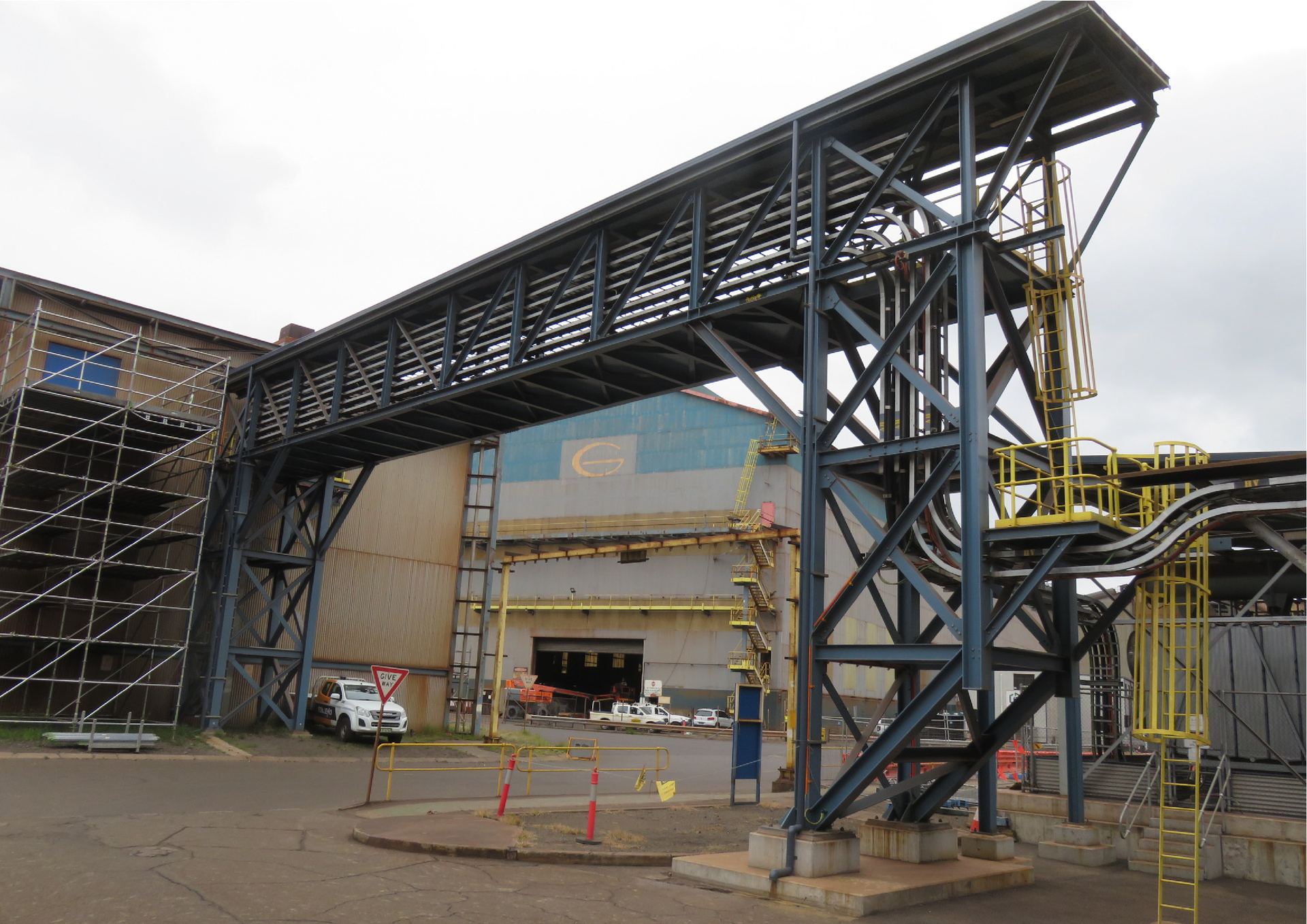 Construction crew using a boom lift on a large industrial building frame under a blue sky