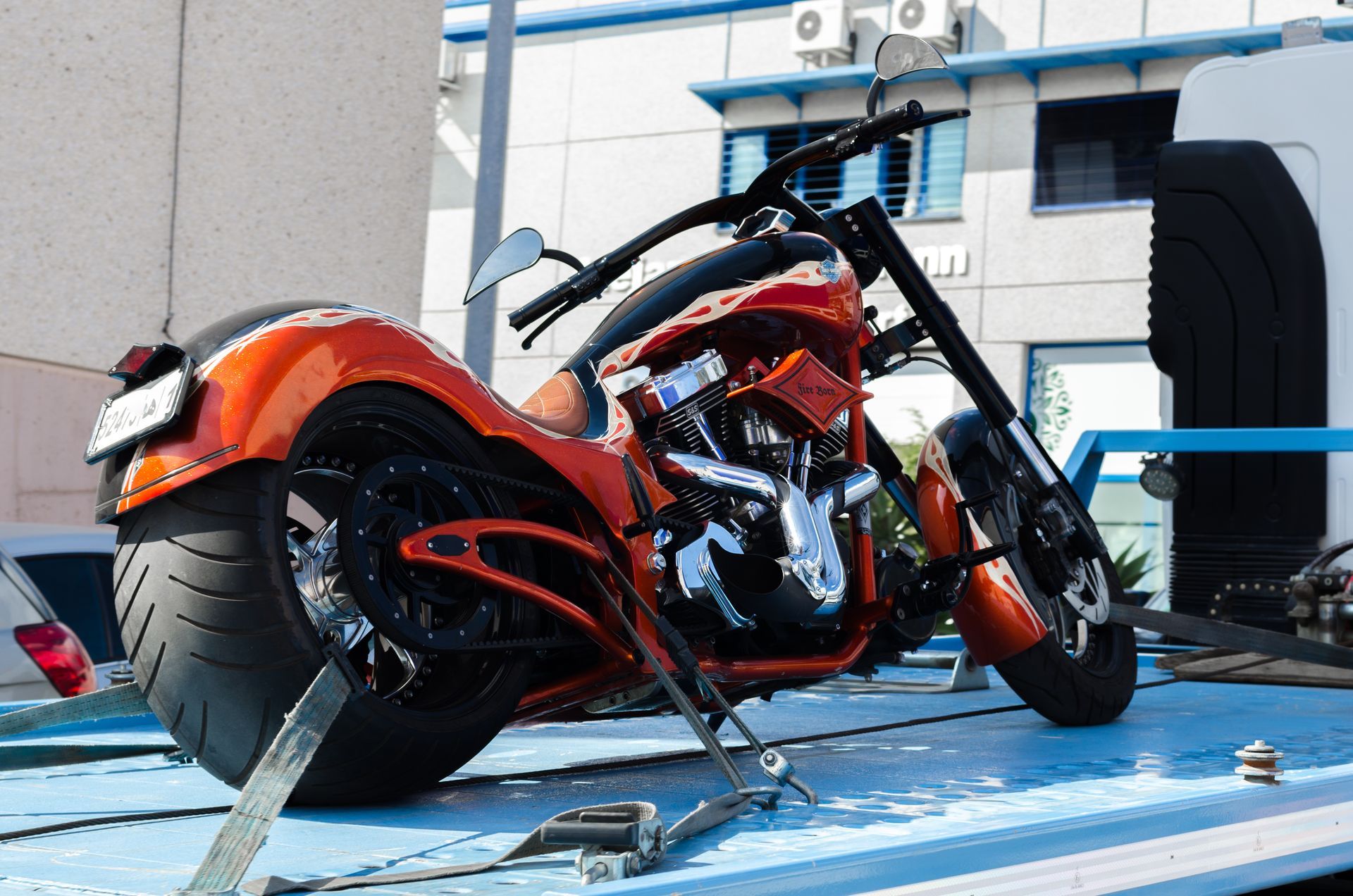 Red custom chopper motorcycle parked on a blue platform outside a building.