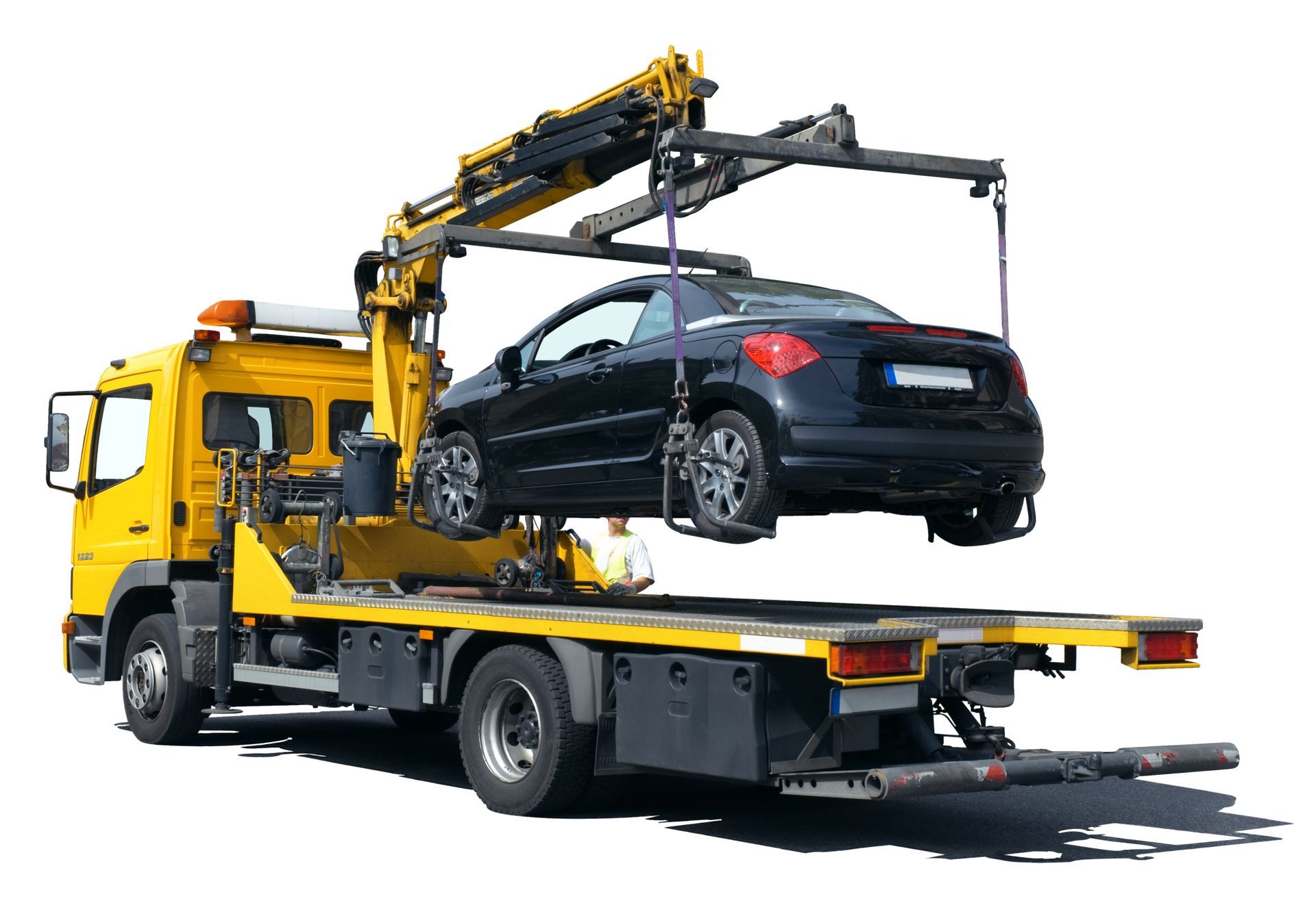 Yellow tow truck carrying a black sedan on a flatbed with a crane arm raised