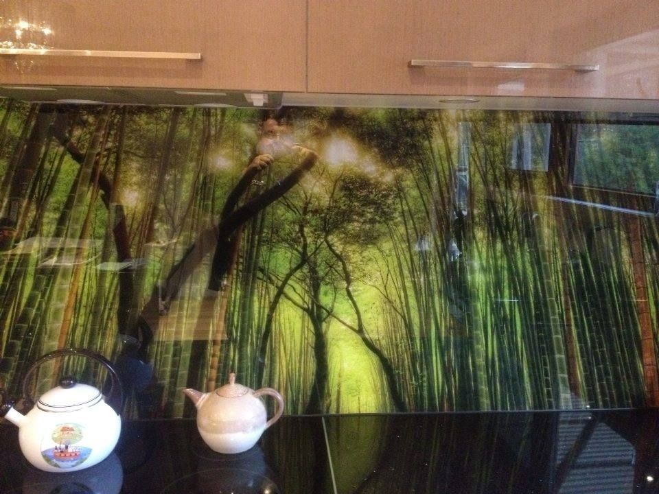 Kitchen backsplash with forest scene and two teapots.