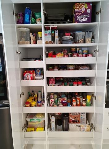 Open pantry with shelves and drawers filled with various food items.