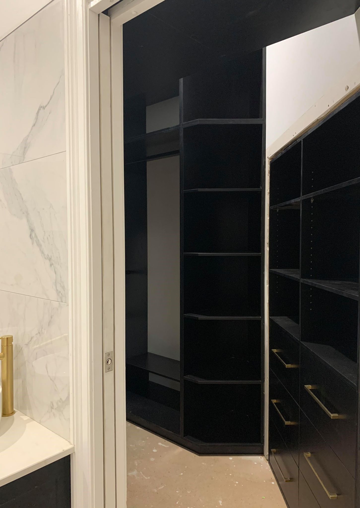 Walk-in closet with black shelving and open doorway, white walls.