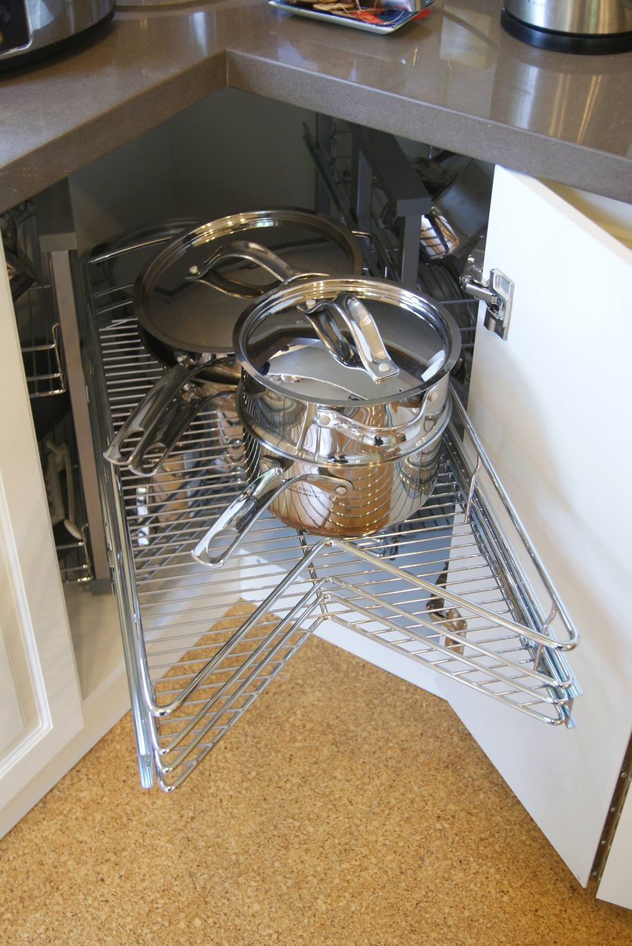 Corner kitchen cabinet with pull-out shelving holding pots and pans.