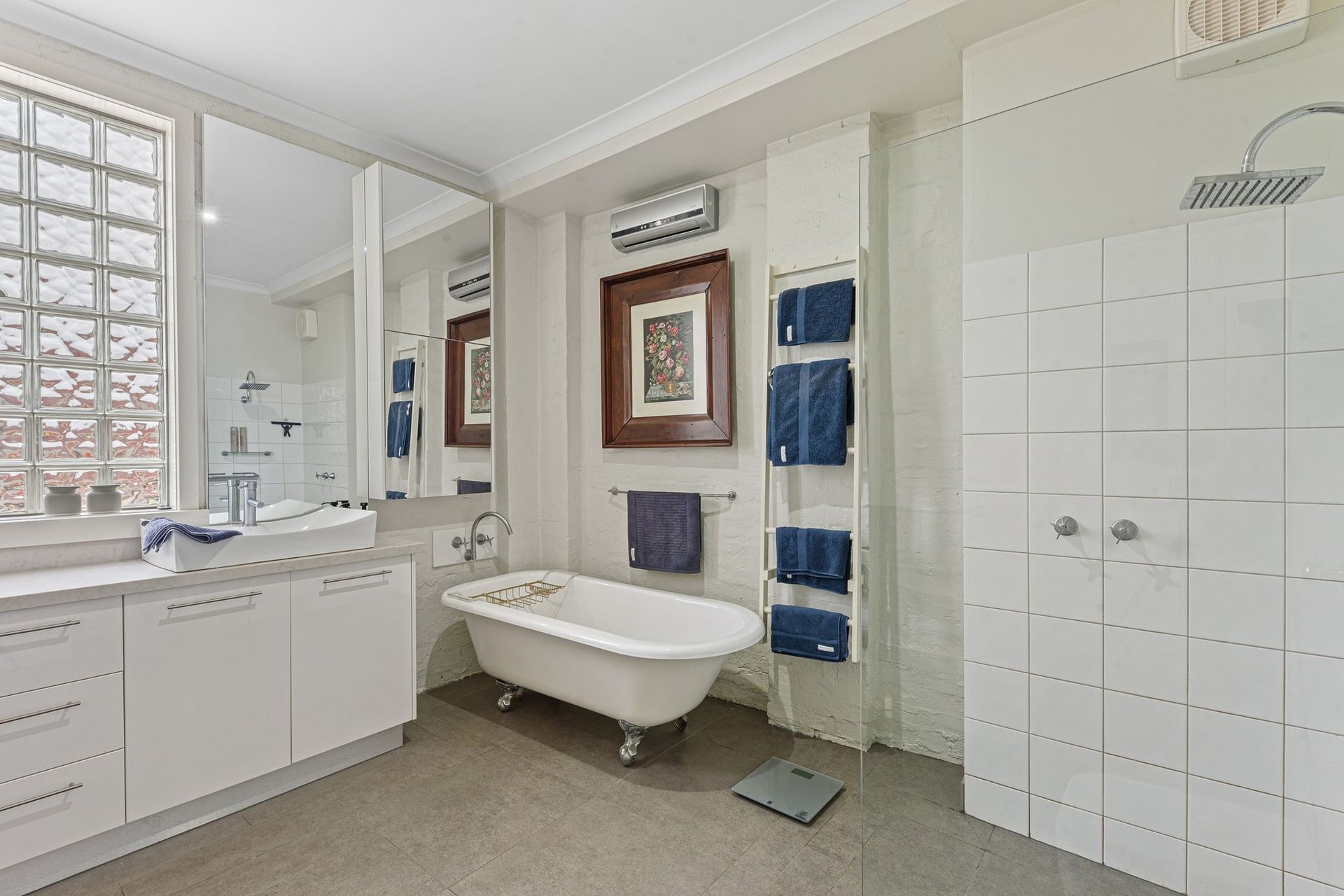 A person in work clothes applies sealant to the top of a white bathroom vanity.