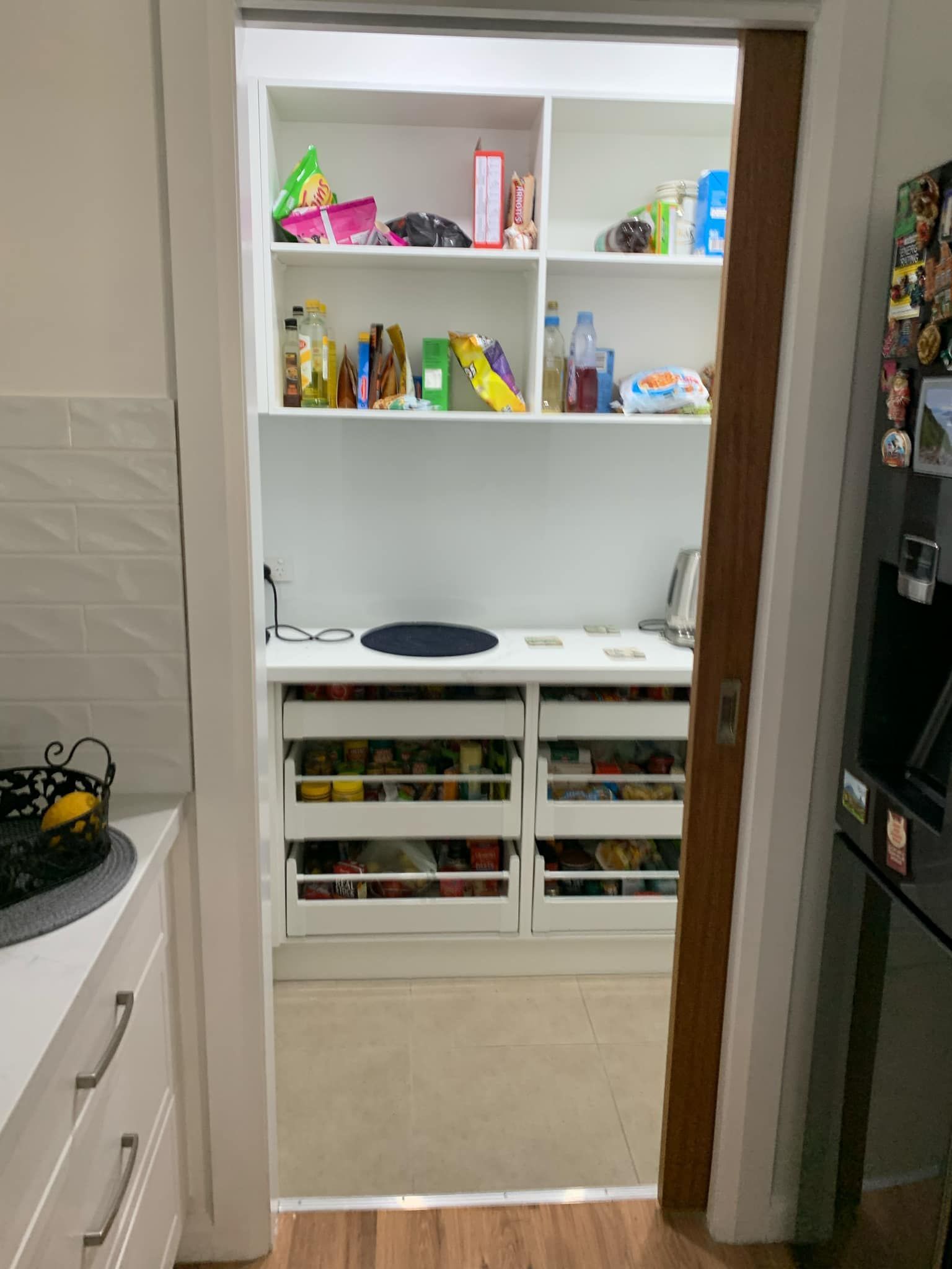 Pantry with white shelves and pull-out drawers, open from the kitchen.