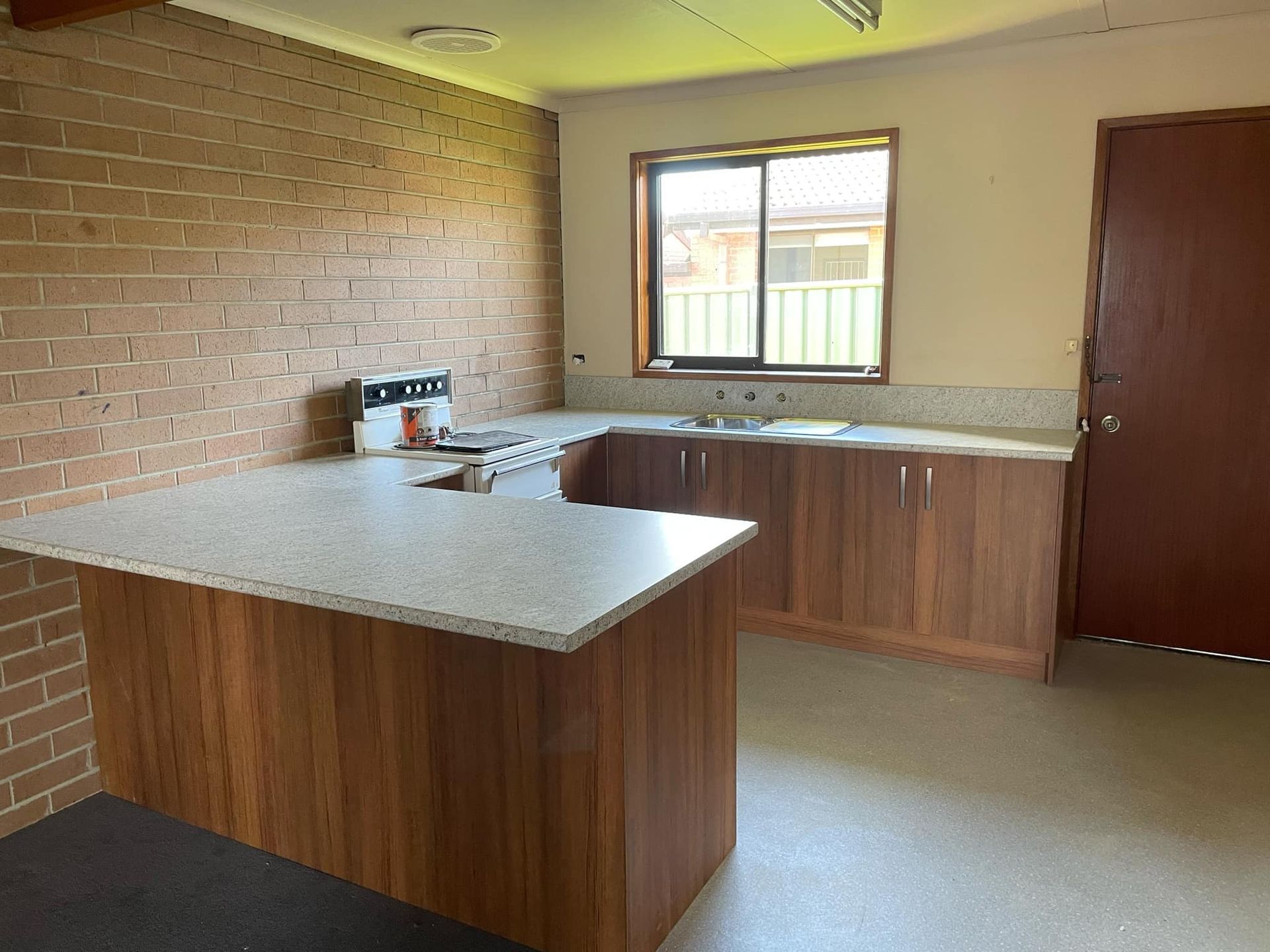 Kitchen with wood cabinets, brick wall, and a window.