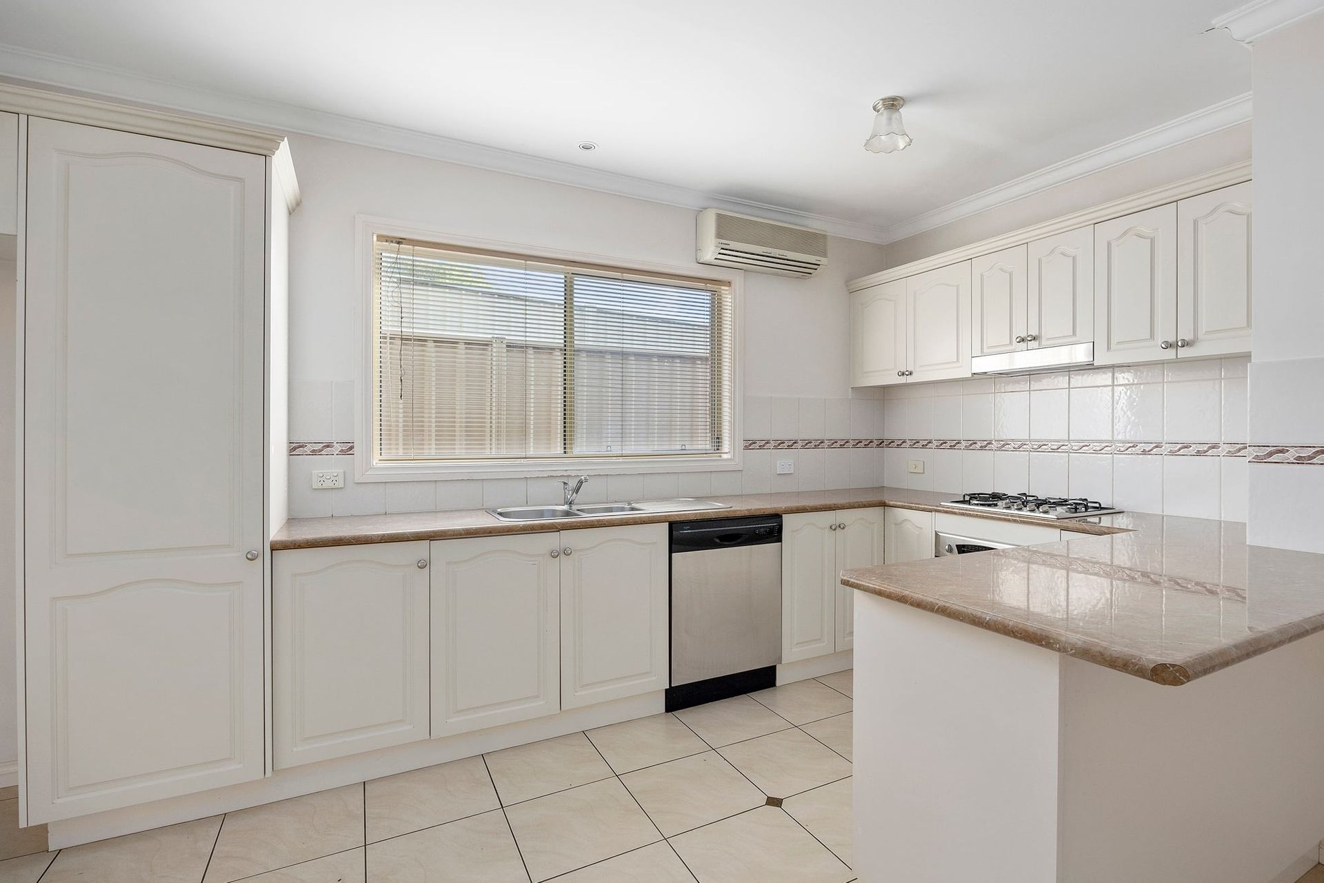 White kitchen with cabinets, countertops, and appliances. Includes a window and an island.