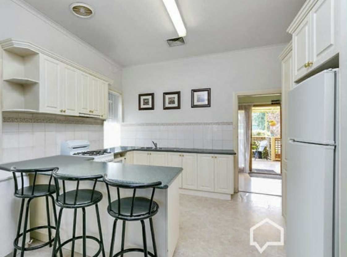 Kitchen with a breakfast bar, white cabinets, and a doorway leading to an outdoor area.