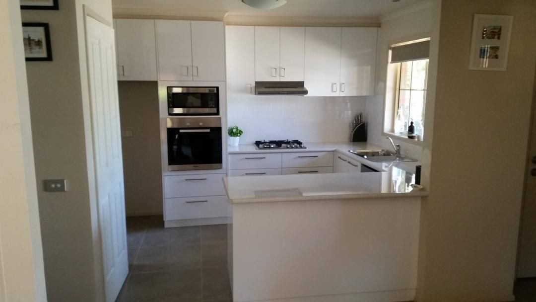 White kitchen with upper and lower cabinets, built-in appliances, and a countertop.