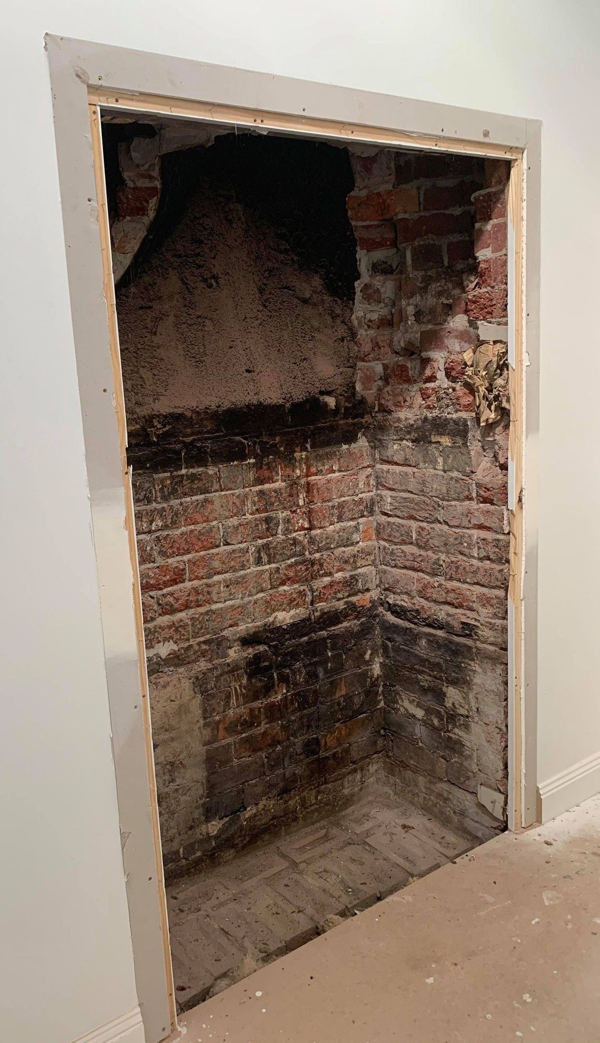 Brick wall exposed in doorway frame. Dark stains and remnants visible on the brick.