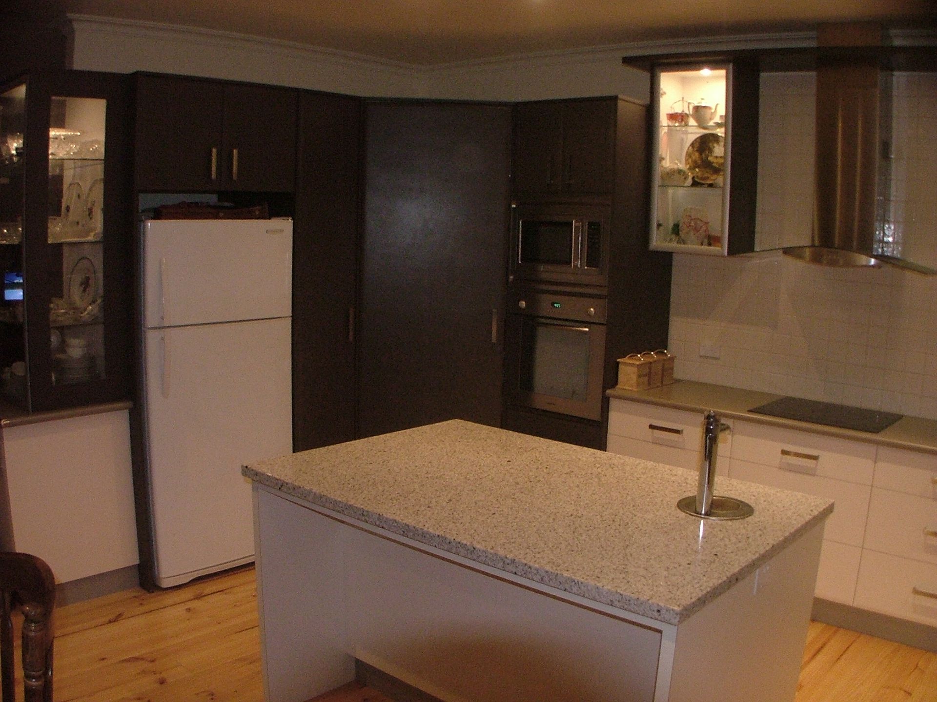 Kitchen with dark cabinets, white refrigerator, island, and light countertop.