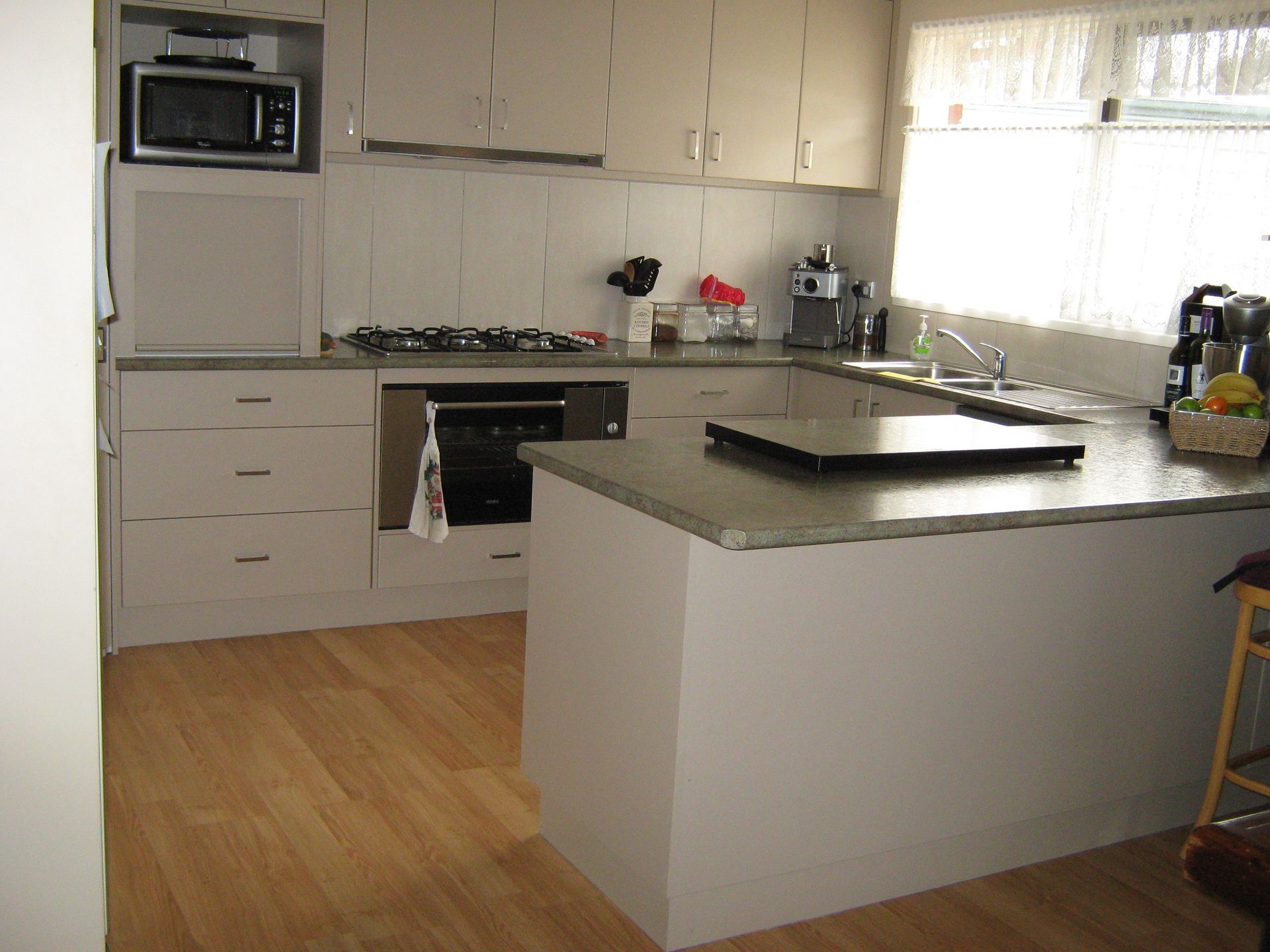 Kitchen with light cabinets, an island, and wood floors. A microwave sits above the stovetop.