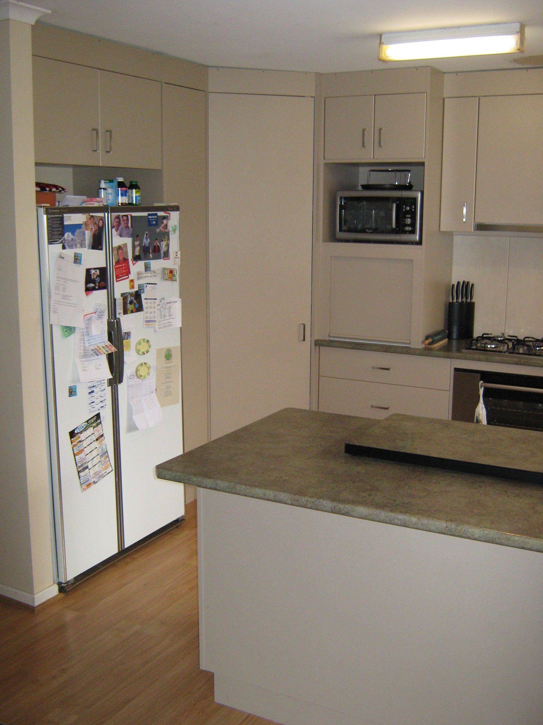 Kitchen with light-colored cabinets, a refrigerator covered in notes, and a countertop island.