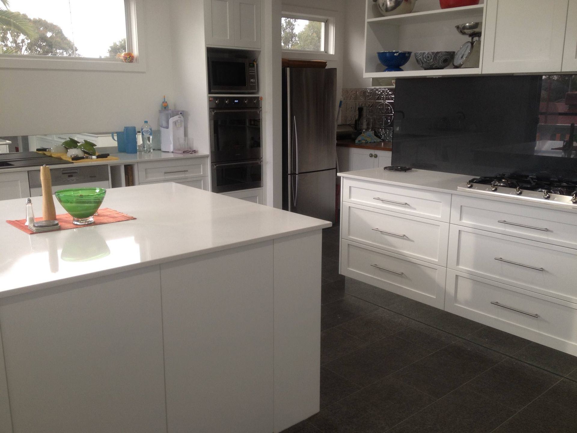 White kitchen with island, cabinets, stainless steel appliances, and a dark floor.