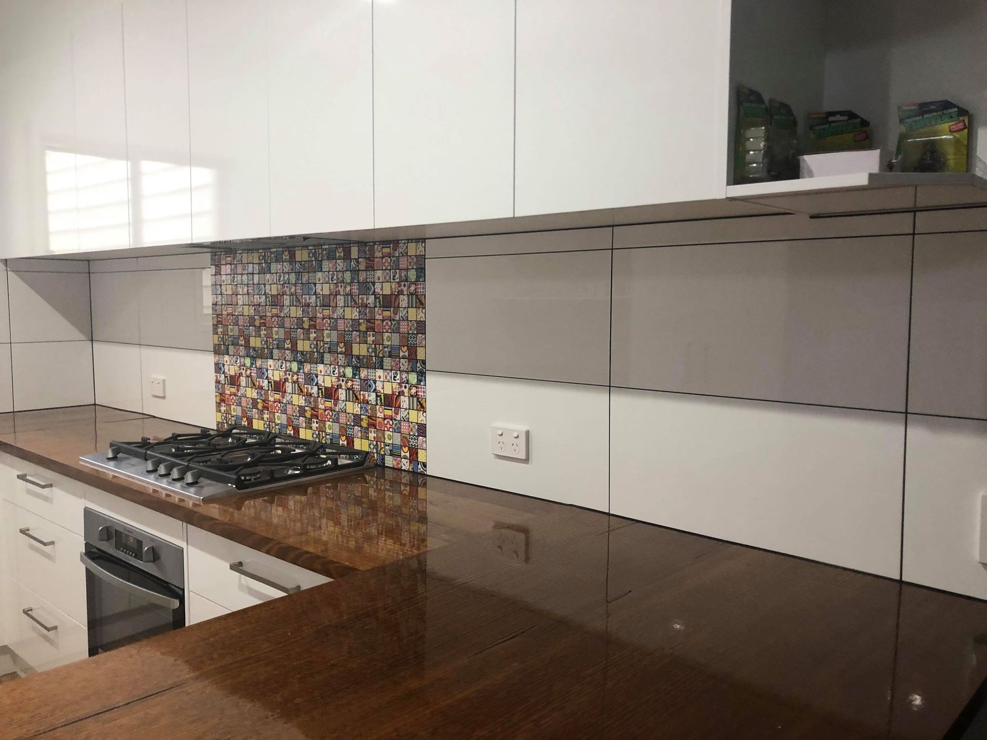 Modern kitchen with white cabinets, dark wood countertop, and patterned tile backsplash.