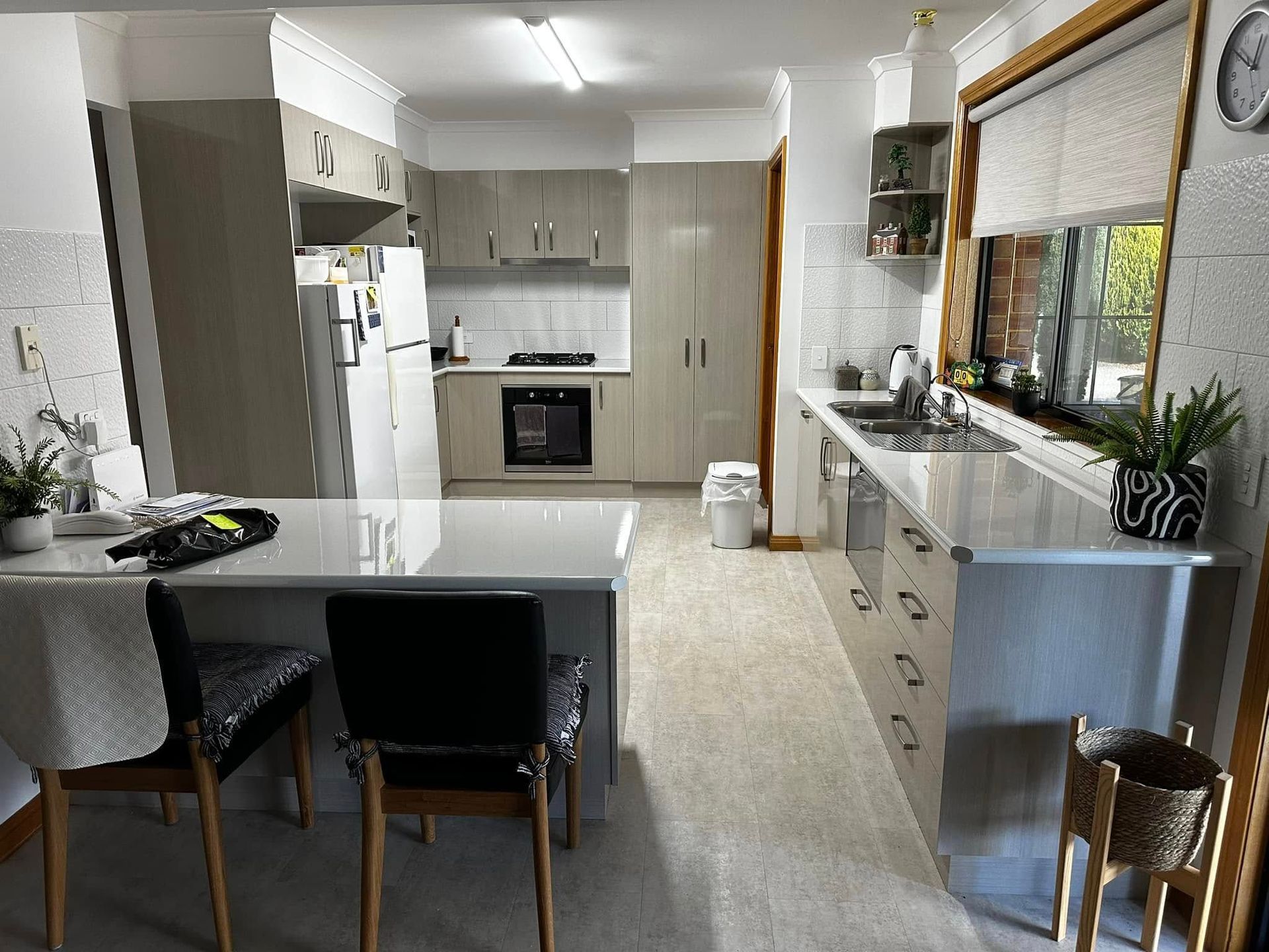 Kitchen with light gray cabinets, white countertops, and bar seating.