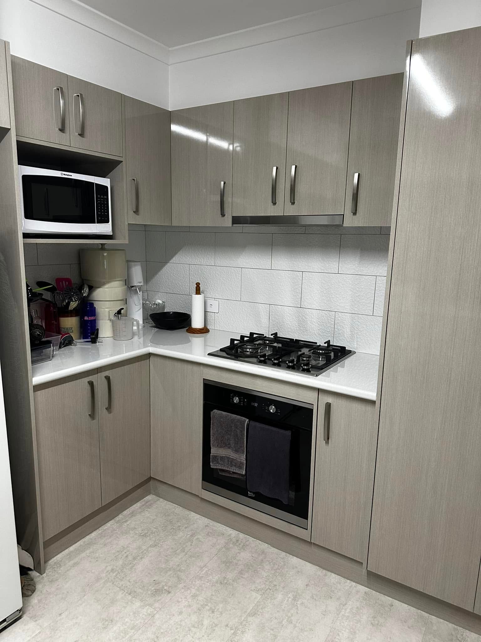 Small kitchen with beige cabinets, white countertops, and stainless steel appliances.