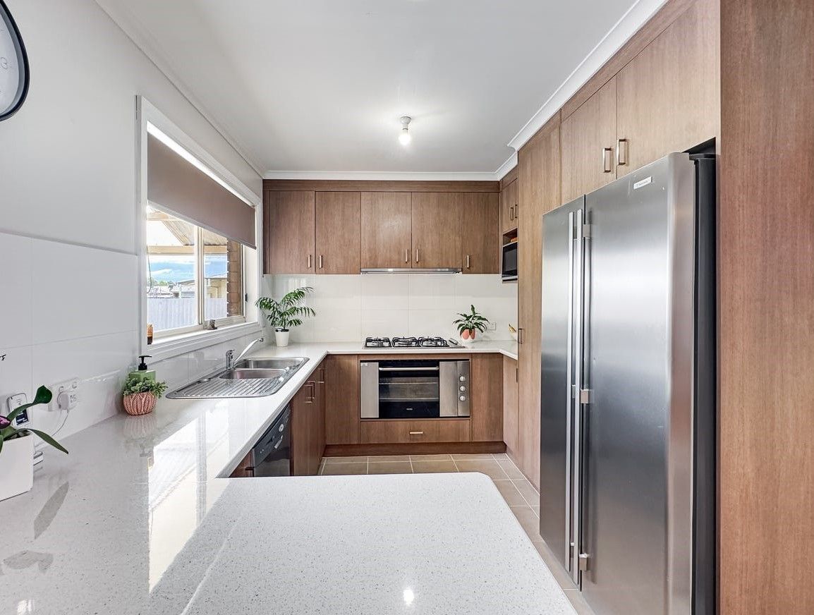 Kitchen with wooden cabinets, stainless steel refrigerator, and white countertops.