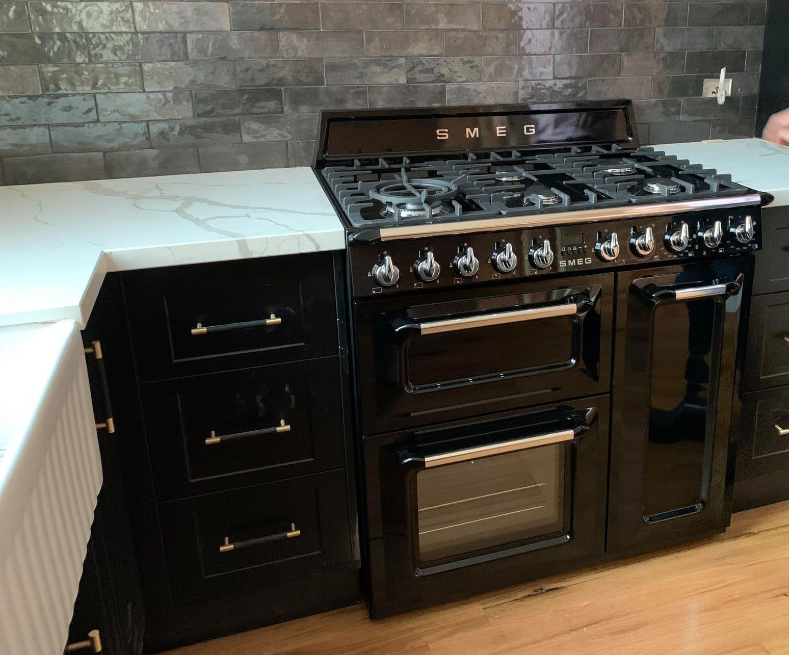 Black stove and cabinets in a modern kitchen with a stone backsplash and white countertop.