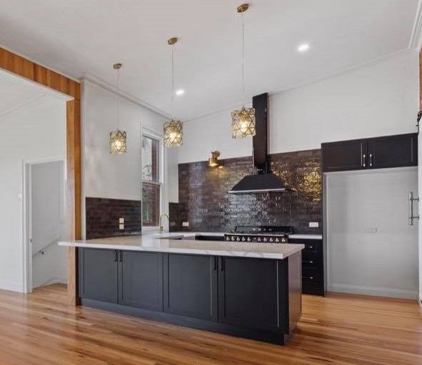 Modern kitchen with a black island, white countertops, and wood floors.